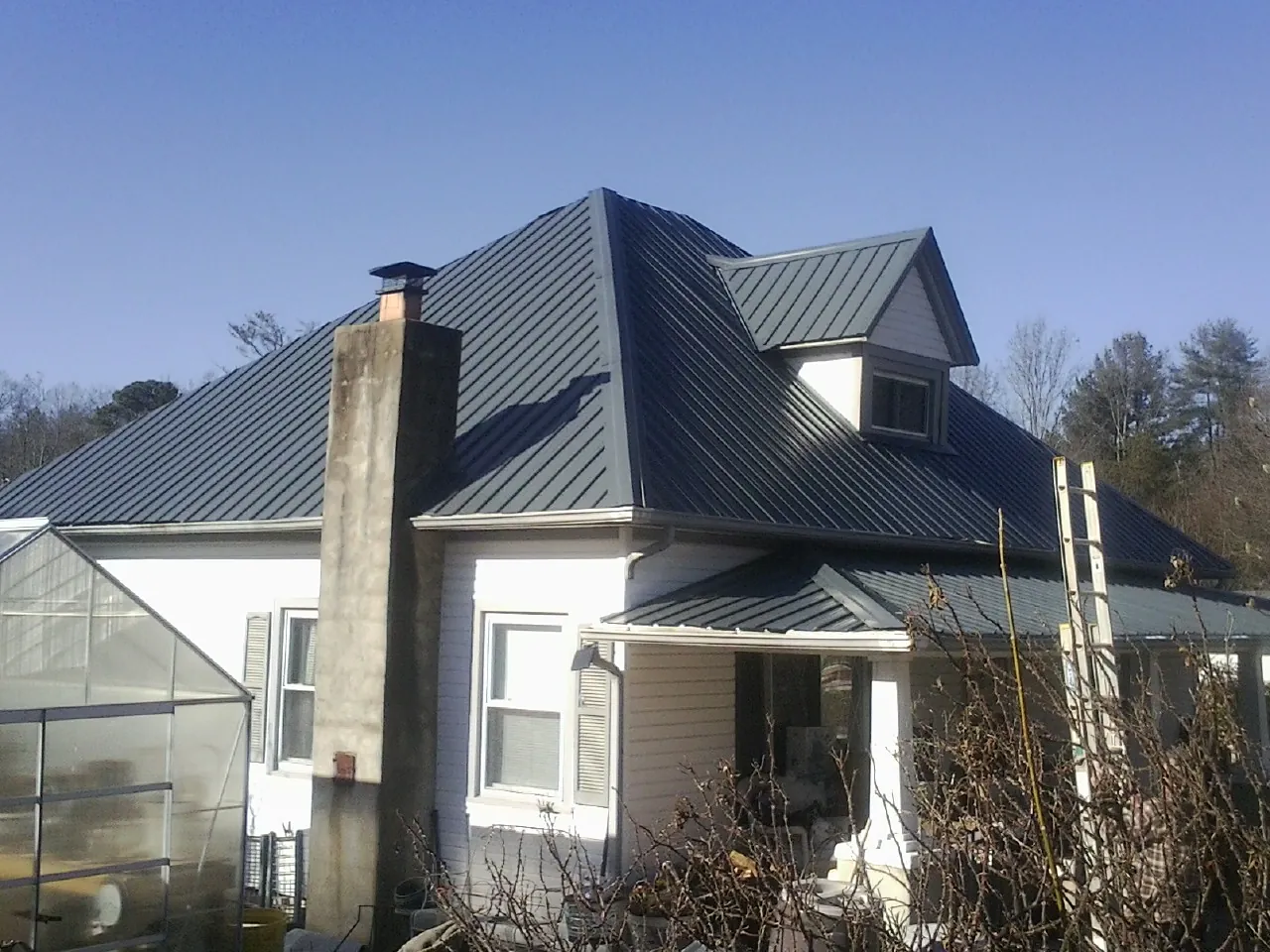 Dark blue standing seam metal roof on a white farmhouse with dormer — Slate & Tile Roof Repair by Roofing Brothers in Marsing