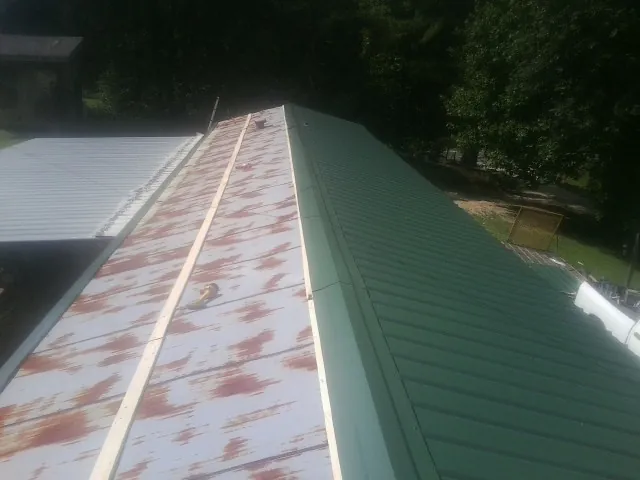 Old rusted panels beside newly installed green metal roofing — Wind Damage Roof Repair by Roofing Brothers in Marsing