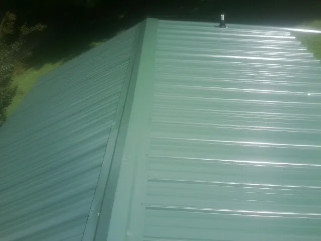 New green metal panels meeting at the ridge of a roof — Flat Roof Repair work by our crew in Marsing