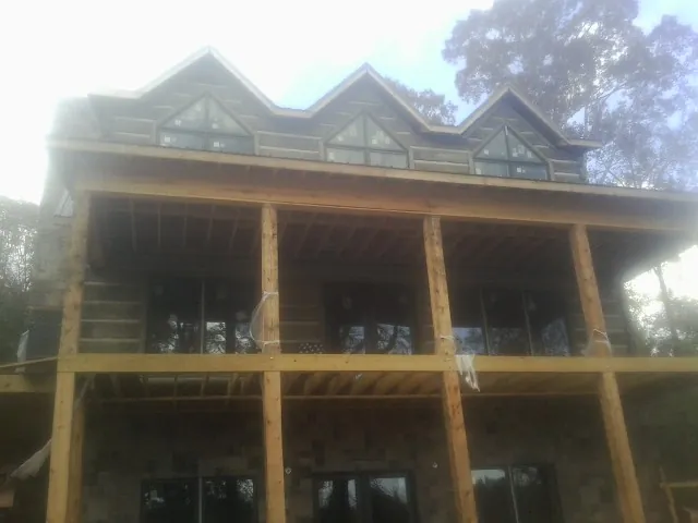 Dormers and porch framing on a large log home under construction — Roof Coating work by our crew in Marsing