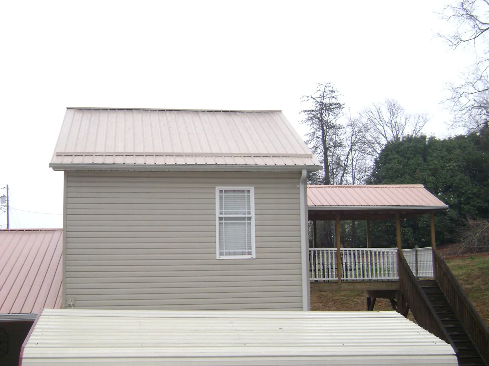 Tan metal roofs on a two story addition and attached porch, from a Roof Replacement job in Marsing